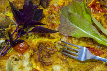 Fish baked in the oven in an egg with tomatoes, lettuce and basil.
