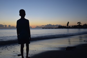 Silhouette d'un enfant qui regarde le coucher de soleil