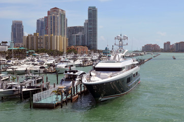 Fototapeta na wymiar Mega luxurious motor yacht docked at a marina in Miami Beach with luxury high-rise condominiums over looking the marina and the Atlantic Ocean in the background.