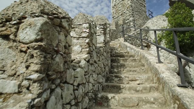 POV climbing walls of Castle of the Moors. The Moorish fortress is a medieval castle and Unesco Heritage on top of a hill above Sintra, Portugal. On right aerial view of Sintra National Palace