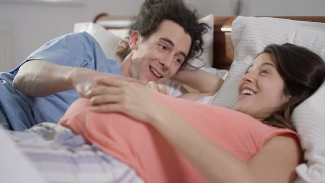  Happy couple expecting a baby relaxing together in bed