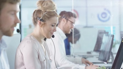  Portrait smiling customer service operator taking calls in busy call center