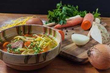 Chicken soup with noodles on rustic wooden table