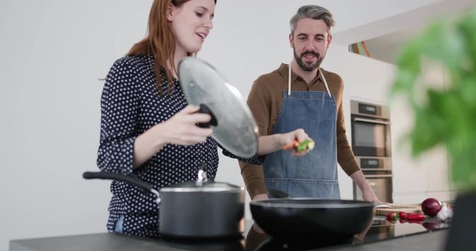 Couple tasting food whilst cooking
