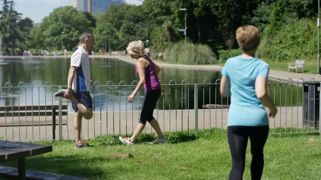  Mature couple working out in park, smartphone with fitness app in foreground