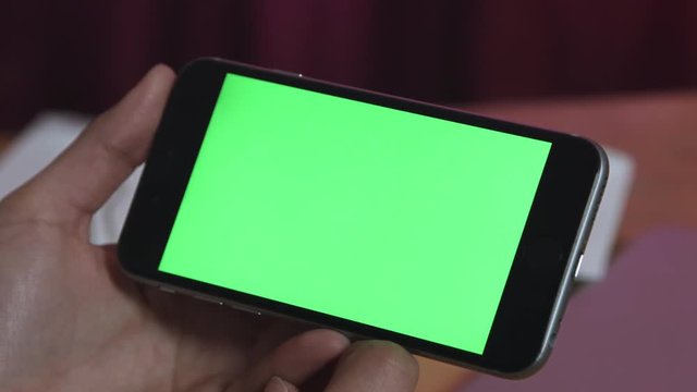 Hold smart phone with green screen in landscape