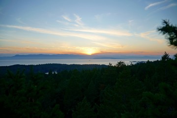 Aussicht vom Wald auf das Meer mit Sonnenuntergang und Wald.