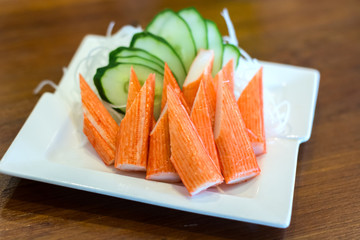 Crab sticks in a white dish placed on a table.