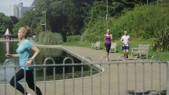  Healthy mature man & woman stop to take a break from running in the park