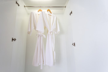 two off white color bathrobes hanging in closet, room for copy space