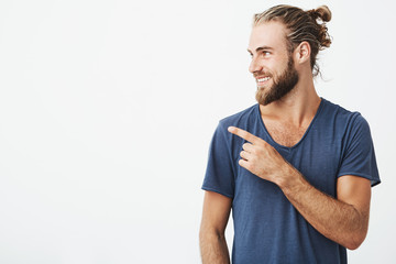 Profile of cheerful handsome man with fashionable hairstyle and beard smiling brightfully and...