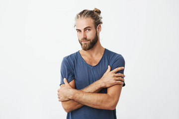 Close up portrait of attractive bearded man with good-looking hairstyle crossing hands on chest, looking at camera with flirty expression. - obrazy, fototapety, plakaty