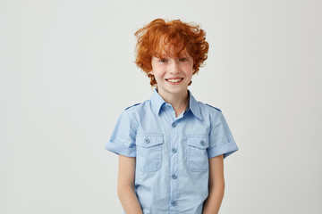 Close up of beautiful little ginger boy with tousled hair and freckles, laughing and looking in...