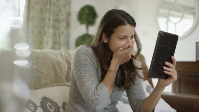  Sad woman making emotional video call on computer tablet