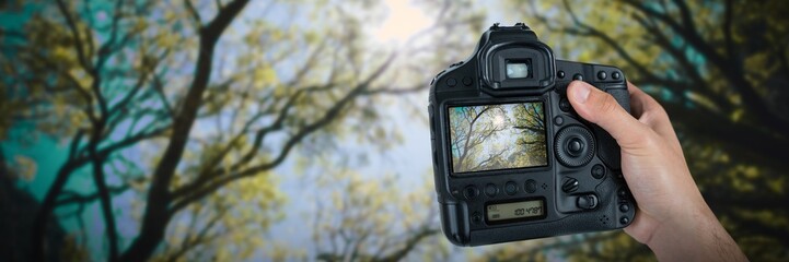 Composite image of cropped hand of photographer holding camera 