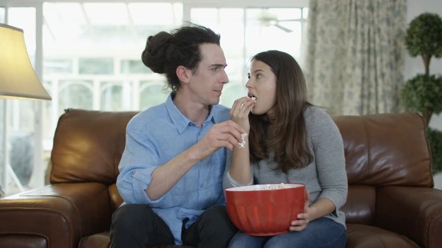  Couple watching TV & eating popcorn, shocked reaction the action on screen