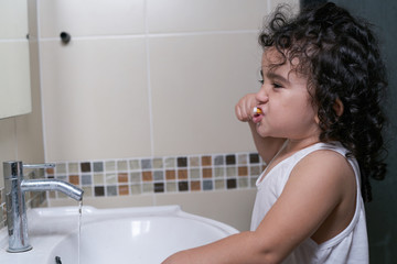Little beautiful girl brushing teeth in bathroom, healthy concept