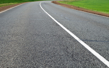 Fototapeta na wymiar Highway. Horizontal frame. The asphalt road of the road with white markings goes to the horizon surrounded by green fields
