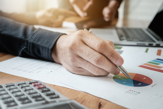 Young business man hand holding pen pointing at chart with partn