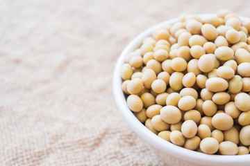 Closeup soy beans on white bowl with sackcloth background , healthy food concept
