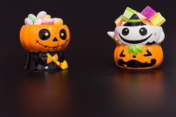 Halloween pumpkin doll head Jack lantern with candy on black background ,trick or treat