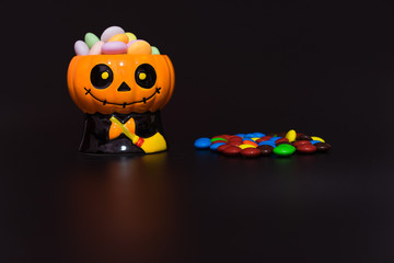 Halloween pumpkin doll head Jack lantern with candy on black background ,trick or treat