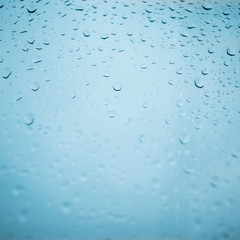 Drops of rain on blue glass background. Natural Pattern of raindrops. Rain in the city.