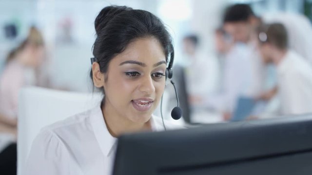  Friendly customer service adviser talking to a customer in busy call center