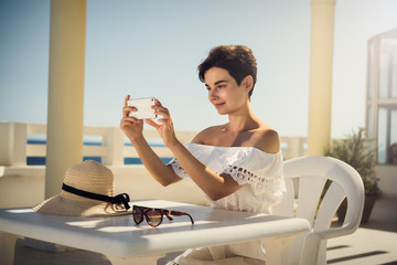 A girl in a white dress is taking pictures with a phone. Rest, travel, vacation. Tunisia.