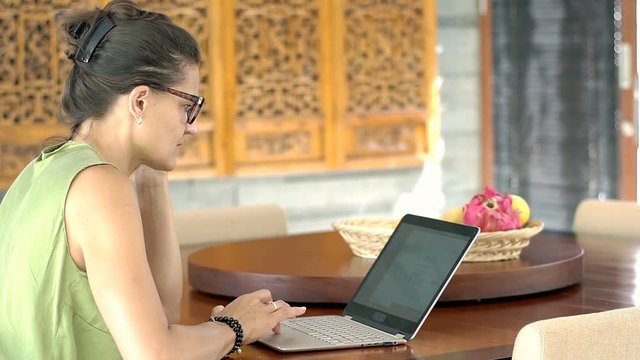 Woman sitting in the dining room and using notebook, steadycam shot
