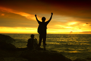Fototapeta na wymiar silhouette of man standing enjoying on a stone tropical sunset