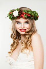 Naklejka premium Beautiful Christmas Woman Fashion Model Woman with Wavy Hairstyle, Makeup and Christmas Wreath with Red Glass Balls, Xmas Tree Twig and Berry