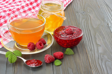 healthy background. raspberry with raspberry jam, honey and tea on dark wooden background