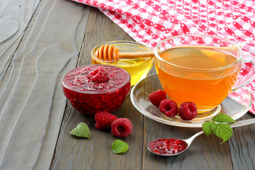 healthy background. raspberry with raspberry jam, honey and tea on dark wooden background