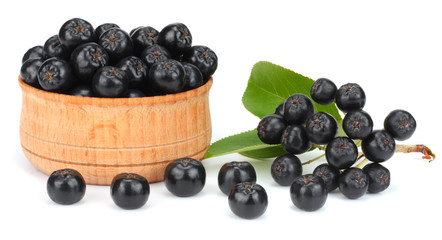 Chokeberry with leaf in wooden bowl isolated on white background. Black aronia