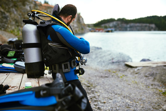 Male diver in wetsuit checking equipments before immerse