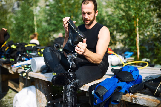 Male diver changing his wet suit and boots after underwater immerse