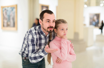 Father and daughter looking at paintings in halls of museum