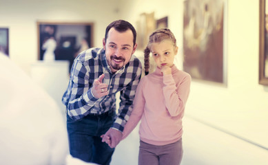 satisfied father and daughter regarding paintings in museum