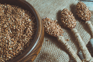 Buckwheat in a wooden bowl and a spoon full of buckwheat on the burlap