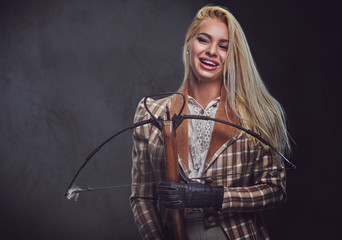 Studio portrait of blond old fashioned female holds a crossbow.
