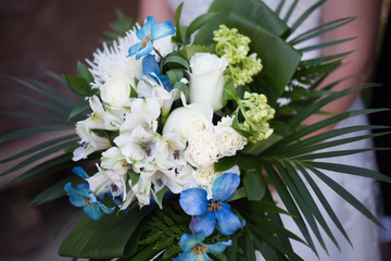 Bride holding a large bouquet of white and blue flower with lush greenery. 