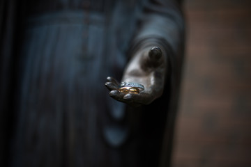 His and her's wedding rings held by a bronze statue hand. 