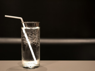 A soft focused image of a glass of cold water with ice on table with the black background