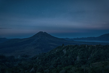 Silhouette of the mountain volcano Batur on background night sky with stars