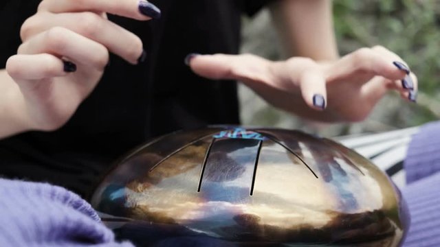 Woman is playing on the steel tongue drum. Close-up. Tank drum. Unusual musical instrument