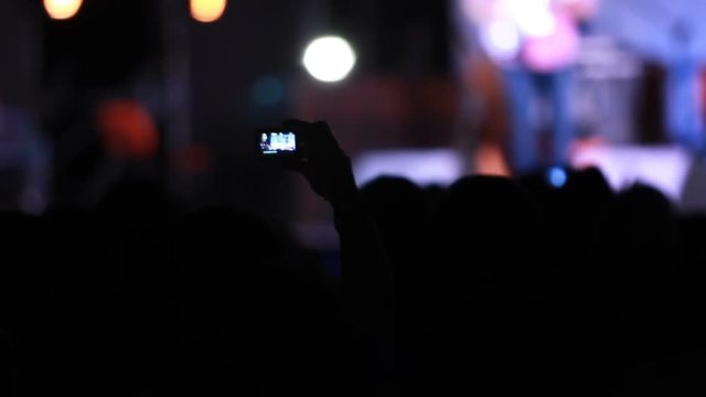 Silhouette of people heads in front of bright scene that take a photo on mobile