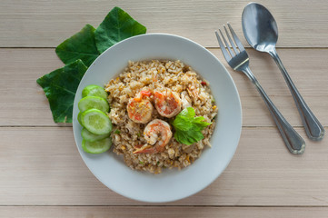shrimp fried rice with spoon and fork on wood plate top view