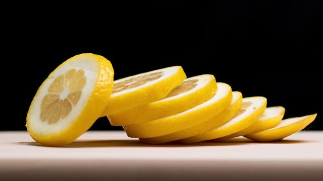 Closeup shot on lemon being cut to slices on black background. 4k stop motion animation.