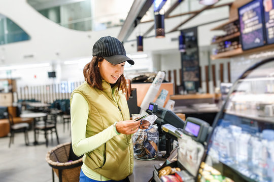 Young woman customer paying with credit card in a coffee shop